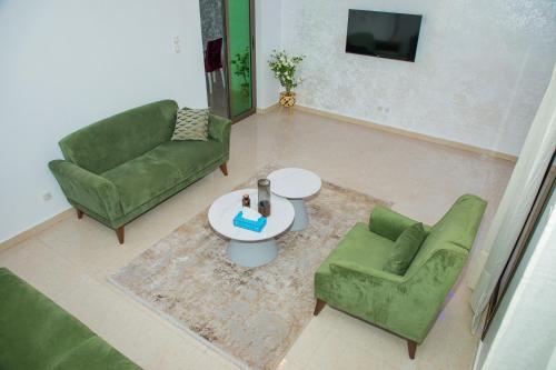 a living room with two green chairs and a table at Résidence FARASELAA in Dakar