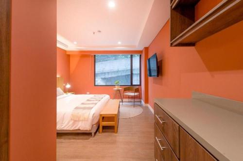 a bedroom with orange walls and a bed and a table at Luxury Escape by El Tesoro Perfect Location 302 in Medellín