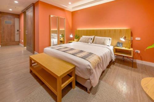 a bedroom with a large bed with orange walls at Luxury Escape by El Tesoro Perfect Location 302 in Medellín