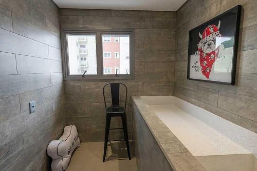 a bath tub with a stool and a window at Metrô Santa Cruz Studio Novo in Sao Paulo