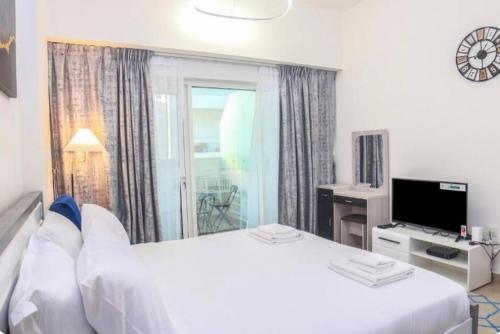 a hotel room with a white bed and a window at Cozy, fully furnished, Kitchen equipped Studio apartment with all facilities in Dubai
