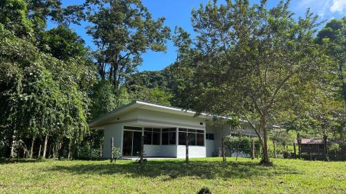 a small white house in a field with trees at Mei Tai Cacao Lodge in Bijagua