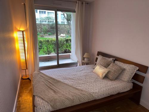 une chambre avec un lit et une grande fenêtre dans l'établissement Le cosy du 12ème, à Paris