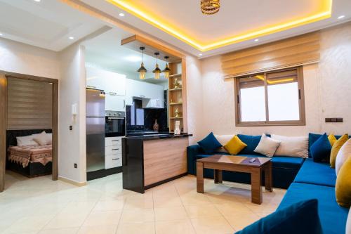 a living room with a blue couch and a kitchen at L'horizon Aéroport Appartement in Marrakech