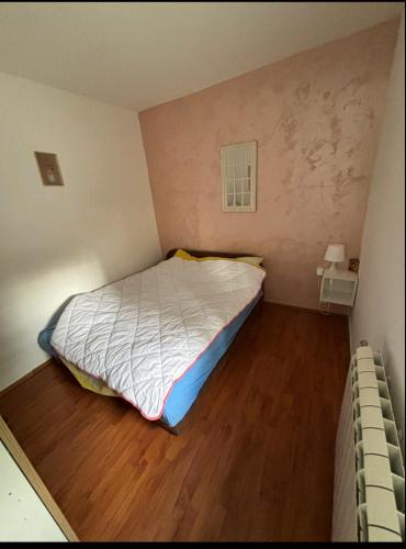 a small bedroom with a bed and a wooden floor at Apartman Šumski San in Divčibare
