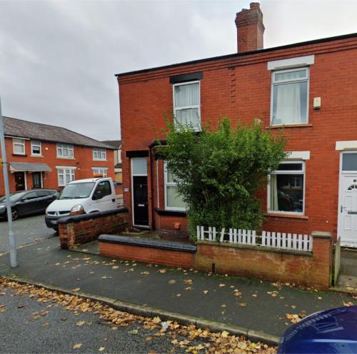 ein Backsteinhaus mit einem davor geparkten Auto in der Unterkunft Spacious 3-Bedroom Family Home in Ince in Ince-in-Makerfield