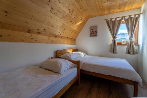 two beds in a room with a wooden ceiling at Vikend Kuća Mirko in Risovac