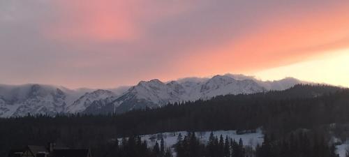 a sunset over a mountain range with snow covered mountains at Siedem Światów in Jurgów