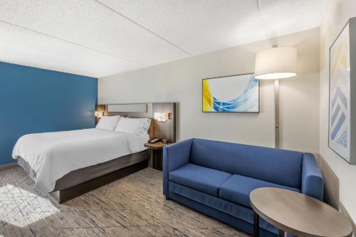 a hotel room with a bed and a blue couch at Holiday Inn Express Crestwood by IHG in Crestwood
