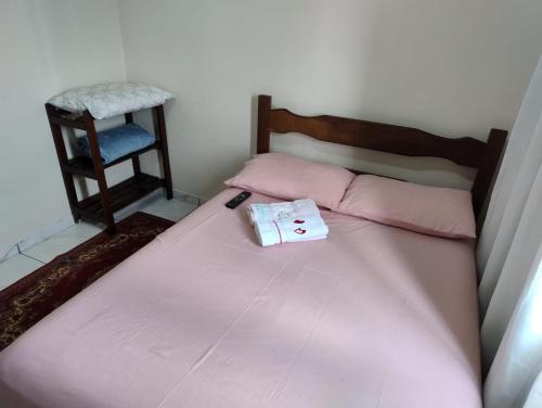 a bed with pink sheets and a chair in a room at Casa Familiar no Centro de Angra in Angra dos Reis