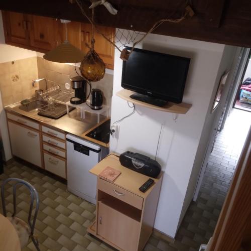 une petite cuisine avec une télévision murale dans l'établissement appartement calme, à Valras-Plage