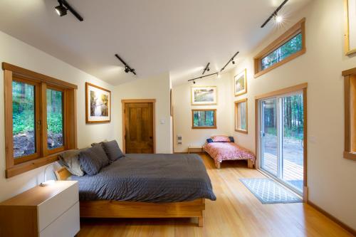 une chambre avec un lit dans une pièce avec des fenêtres dans l'établissement Jordan River Coastal Cottage, à Shirley