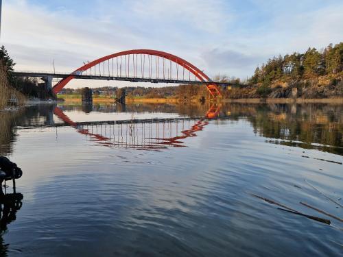 a red bridge over a river in the water at Trevligt fritidshus med underbar utsikt in Gothenburg