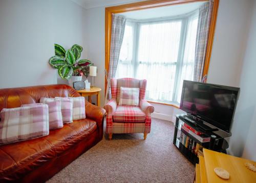 a living room with a couch and a chair and a television at Purple Cloud Cosy 4 bed Cottage with Garden Parking Pet-Friendly in Portsmouth