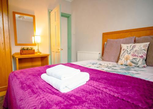 a bedroom with a pink bed with towels on it at Purple Cloud Cosy 4 bed Cottage with Garden Parking Pet-Friendly in Portsmouth