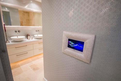 baño con 2 lavabos y TV en la pared en Design Suites Palma, en Palma de Mallorca