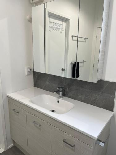 a bathroom with a white sink and a mirror at Starboard Retreat in Mahia