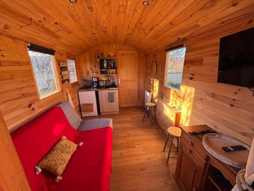 Una sala de estar con un sofá rojo en una cabaña. en La Roulotte Saintaise, en Saintes
