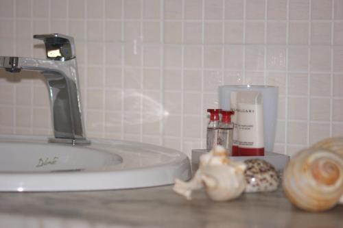 a bathroom sink with a faucet and some cosmetics at Casa Ilva in La Maddalena