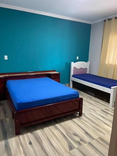two beds in a room with blue walls at Sítio Oásis in Esmeraldas
