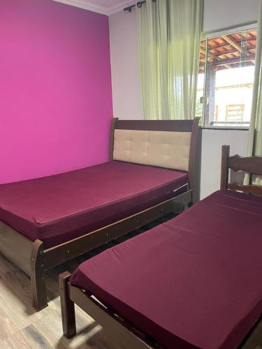 two beds in a room with purple walls at Sítio Oásis in Esmeraldas