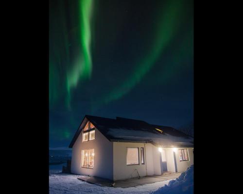 a house with the aurora in the sky at Miðhvammur Farm Stay in Aðaldalur