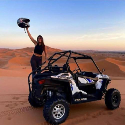 a woman standing in the desert with a wheeler at Rimal Luxury Camp in Merzouga