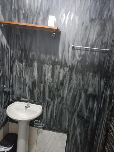 a bathroom with a sink and a black marble wall at casarao24horas in Cuiabá
