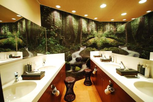 a bathroom with two sinks and a forest mural at Anshin Oyado Ginza Shimbashi Station - For Men in Tokyo