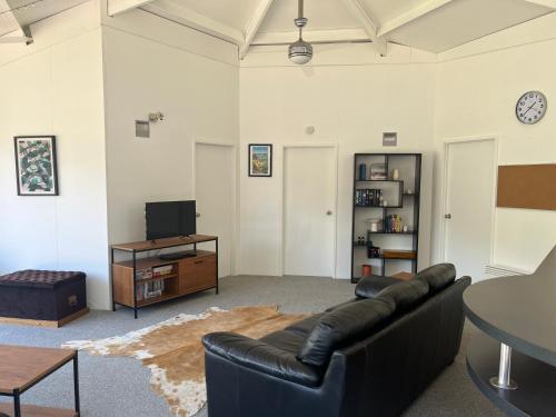 a living room with a black leather couch and a table at Starboard Retreat in Mahia