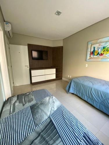 a bedroom with two beds and a tv on the wall at Confortável ampla e com infraestrutura in Capão da Canoa