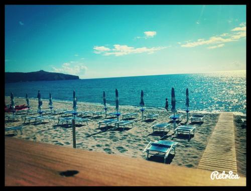 a beach with lounge chairs and umbrellas and the ocean at Residence Il Casale in Palinuro