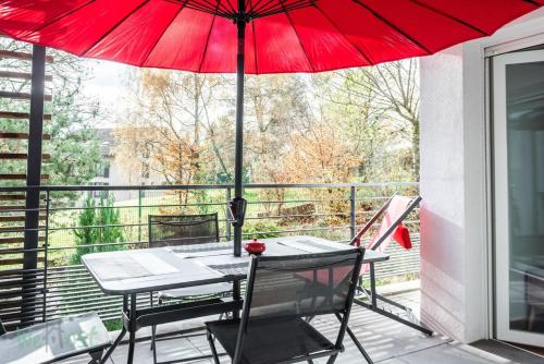 d'une table, de chaises et d'un parasol rouge sur le balcon. dans l'établissement Lachat - LB - Annecy Logement calme et moderne, à Annecy