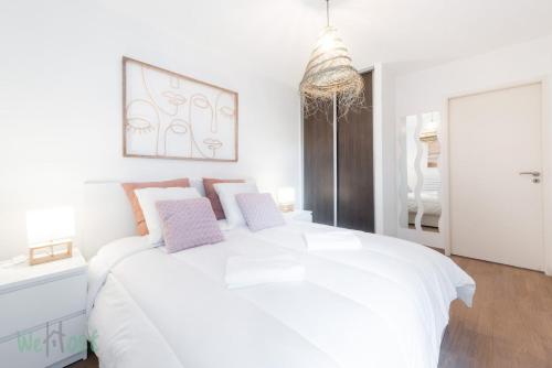 une chambre blanche avec un grand lit blanc avec des oreillers roses dans l'établissement Lachat - LB - Annecy Logement calme et moderne, à Annecy