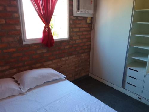 a bedroom with a bed with a brick wall and a window at Wind Villa Cumbuco - Casa in Cumbuco