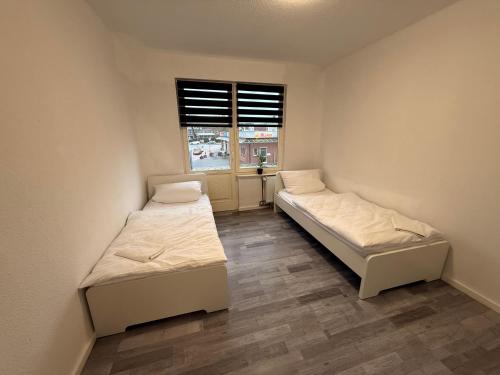 two beds in a room with a window at FeWo 8P 4Z Balkon Küche Zentral in Aurich