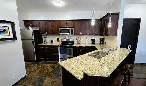 a kitchen with wooden cabinets and a granite counter top at Paradise Resort Club and Spa in Canmore