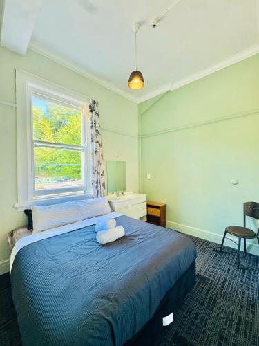 a bedroom with a blue bed with a window at Crashpalace Napier in Napier