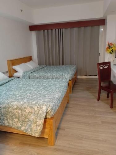 two beds in a room with a chair and a desk at Condo 604 Baguio retreat with pool and gym in Baguio