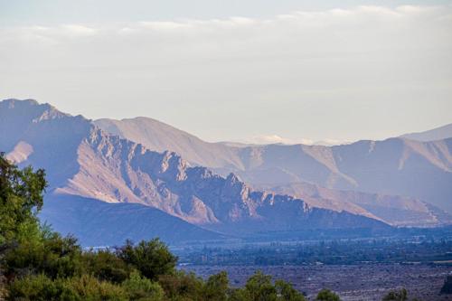 a view of a mountain range with trees in the foreground at Domos El Llano in Putaendo