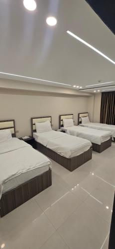 a room with four beds in it with lights at Seven Days Hotel in Irbid