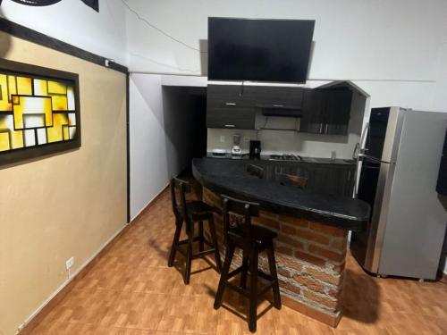 uma cozinha com um bar com cadeiras e uma geladeira em donde la abuela Josefa em Quimbaya