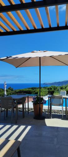 a table and chairs under an umbrella on a patio at Refúgio dos Capelinhos - Villa e Suites in Norte Pequeno
