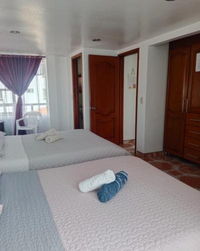 two beds in a hotel room with towels on them at Cabaña Rural BlueHousePaipa in Paipa
