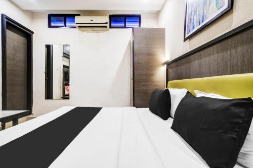a bedroom with a large white bed with black pillows at Super Townhouse Dewas City Formerly Utsav in Dewās