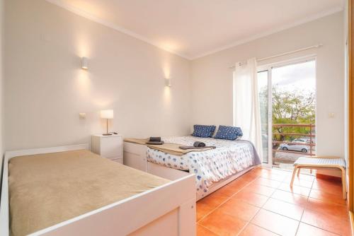 a room with a bed and a desk and a window at Cabanas Beach Apartment in Cabanas de Tavira