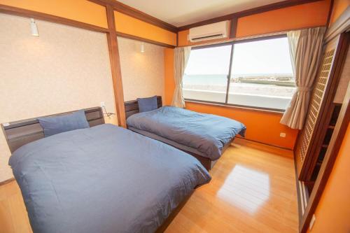 a small room with two beds and a window at Ocean Front Villa Katsuura やどかり in Kawazu