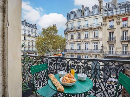 - une table avec du pain et des croissants sur un balcon dans l'établissement Magnificent New Apartment Beaubourg Le Marais, à Paris