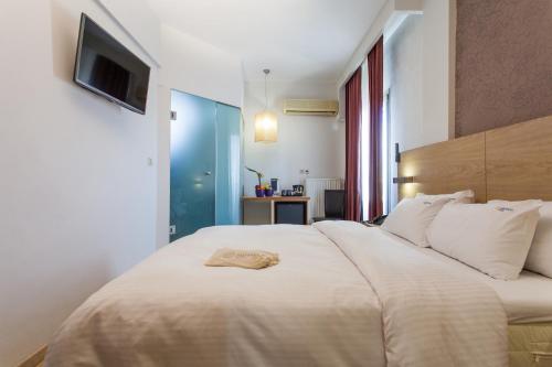 a bedroom with a large white bed with a towel on it at Rotonda Hotel in Thessaloniki