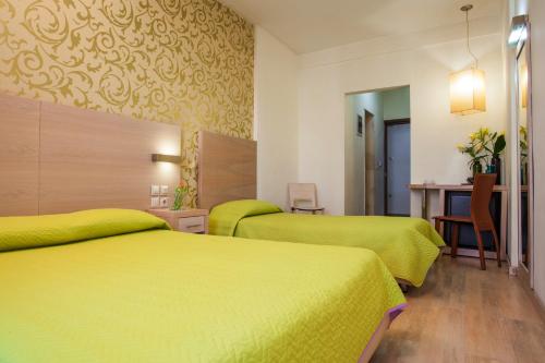 two beds in a hotel room with yellow beds at Rotonda Hotel in Thessaloniki